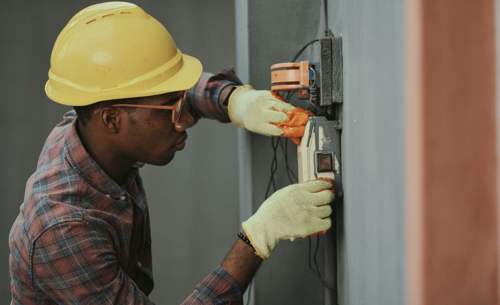 Electrician wiring a wall box in a hard hat
