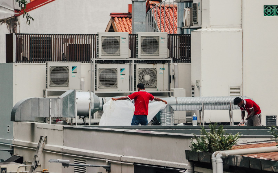 Rooftop bank of split-unit AC condensers being serviced