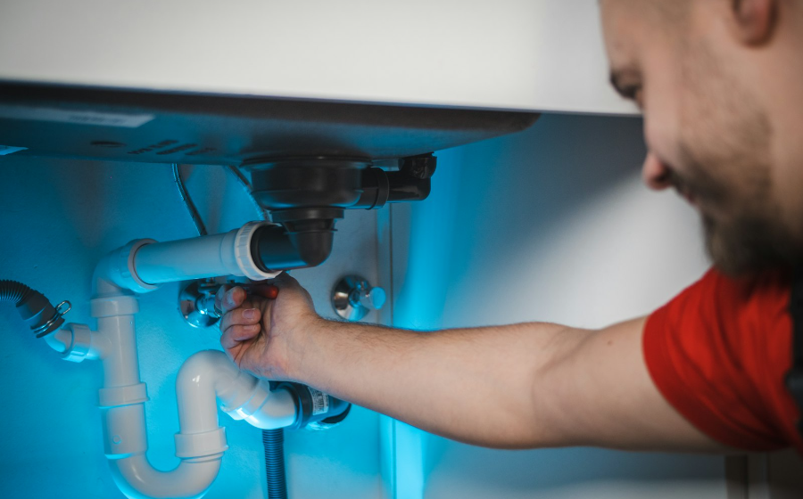 Plumber working on pipes beneath a sink