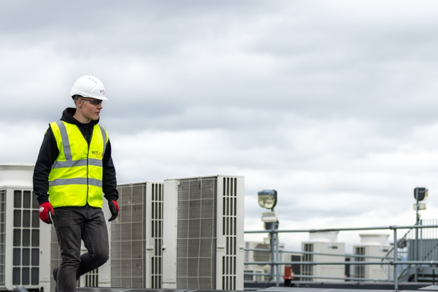 Technician inspecting a rooftop bank of AC condenser units